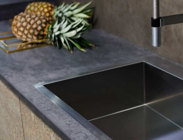 Stainless steel sink with a tap on a kitchen counter.